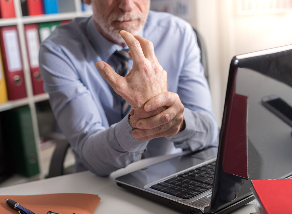 office worker holding is wrist that is in pain from carpal tunnel. The office worker may be entitled to workers' compensation springfield illinois